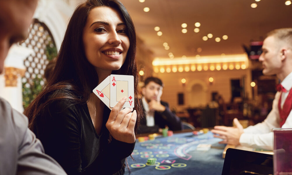 Girl with cards in her hands smiles at winning poker in a casino.